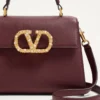 Geantă de mână Valentino Garavani Vsling din piele de vițel granată cu logo bijuterie Geantă de mână Valentino Garavani Vsling din piele de vițel granată cu logo bijuterie